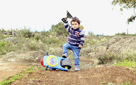 Plano general de niño pequeño levantando trofeo junto a su moto de juguete