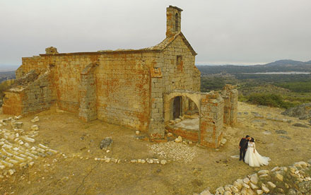 Fotografía aérea de novios junto a capilla en ruinas